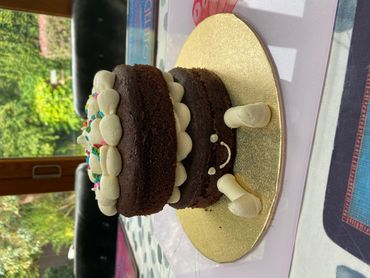 A cute two-layer chocolate cake with frosting and a smiling face.