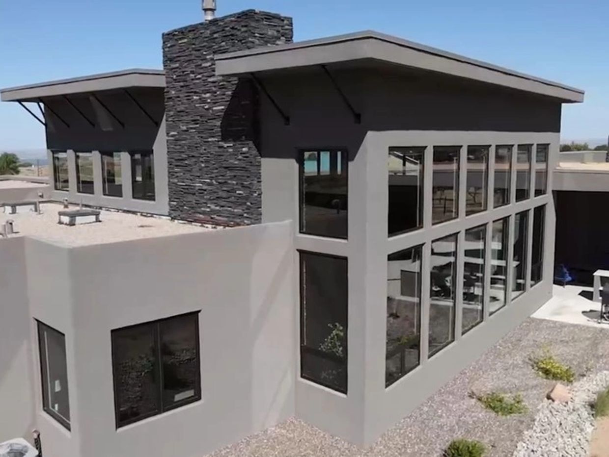 Modern home with large windows and stone chimney.