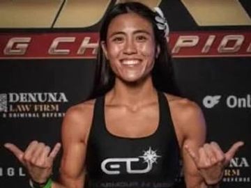 Smiling female athlete posing with thumbs up.