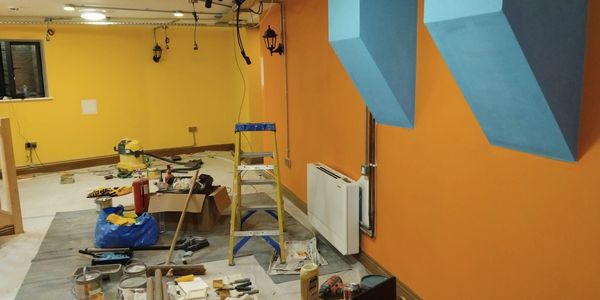 A room under renovation with tools and painting supplies scattered around.