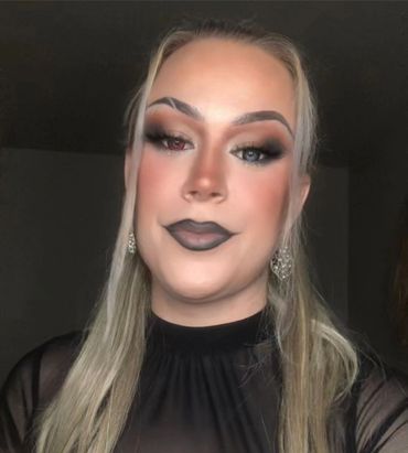 Trans woman with heavy makeup and red and black colored eyes.