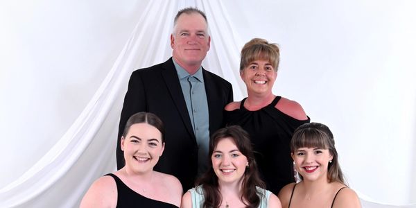 A smiling family portrait with a white backdrop.