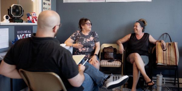 Three people engage in a lively conversation in a casual setting.