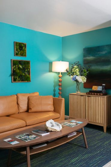 Cozy living room with turquoise walls and tan leather sofa.
