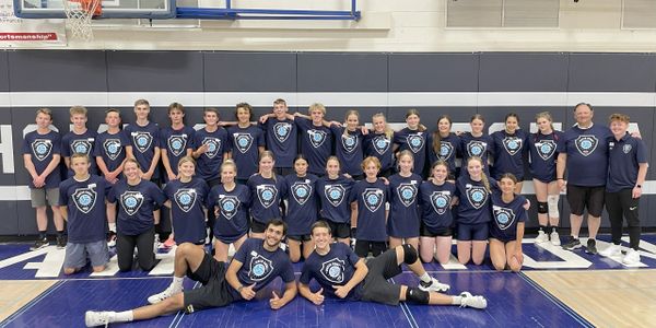 A large group of young athletes and coaches posing in a gymnasium.