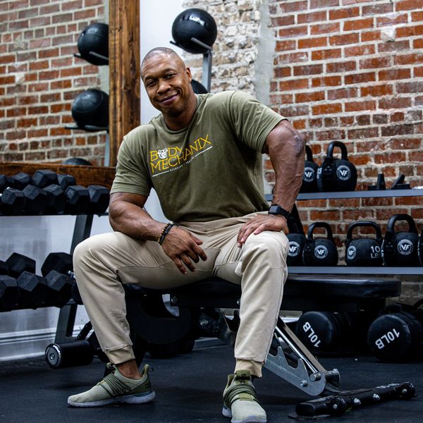 Man sitting on gym bench, smiling.