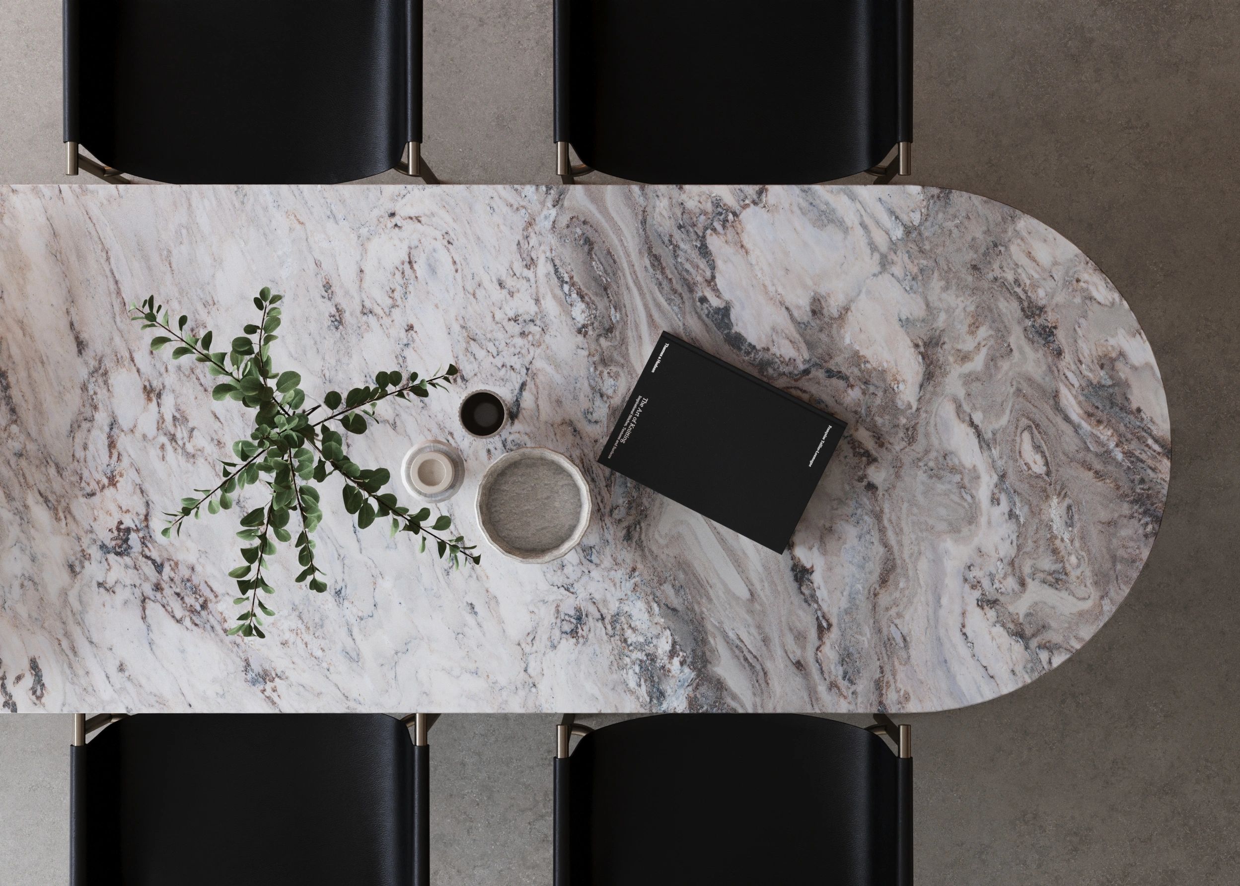 Marble table with black chairs, a book, and decorative items.