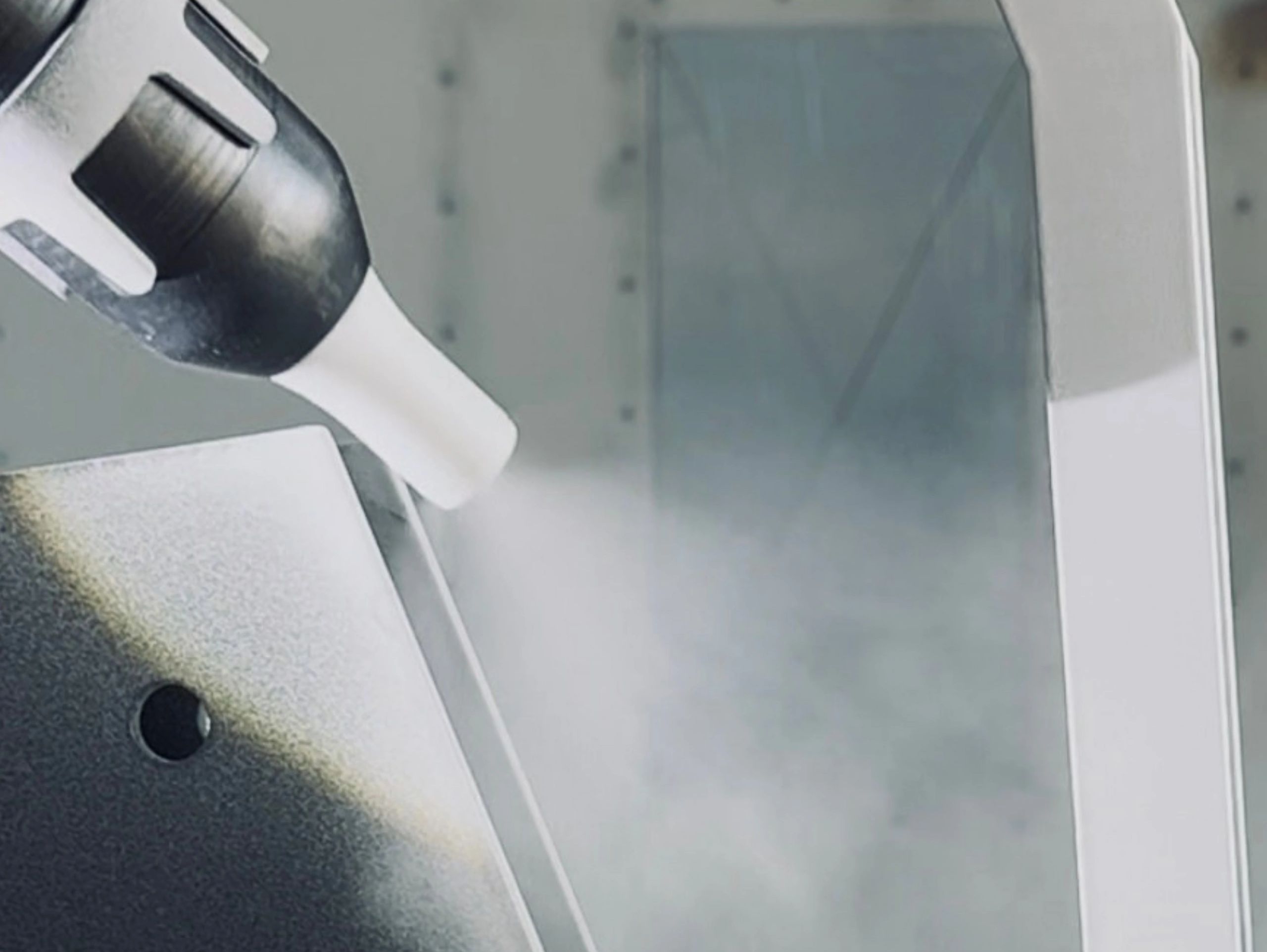 A device spraying a fine mist onto a metallic surface.