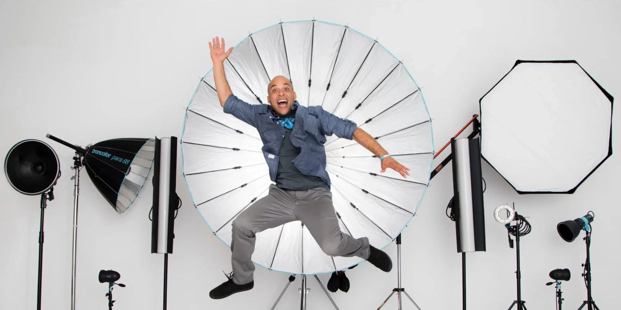 Man joyfully jumping in a professional photography studio with lighting equipment.