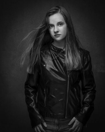 headshot of a young woman actor in a studio wearing a leather jacket