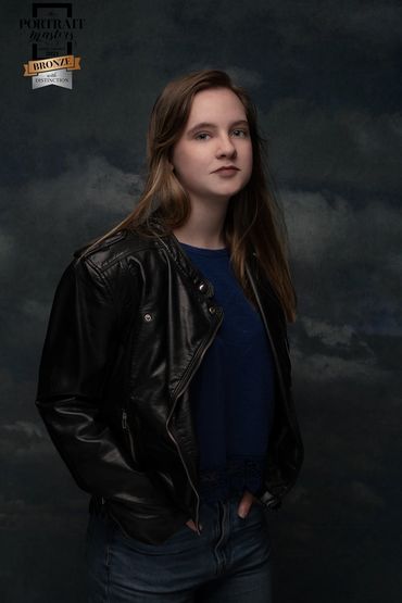 Young woman wearing a leather jacket  with  clouds in the background