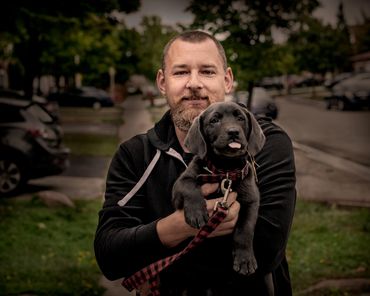 location portrait of man holding a puppy outside