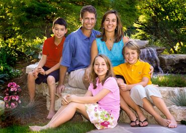 family portrait of five people dressed in a variety of colors in an outdoor setting