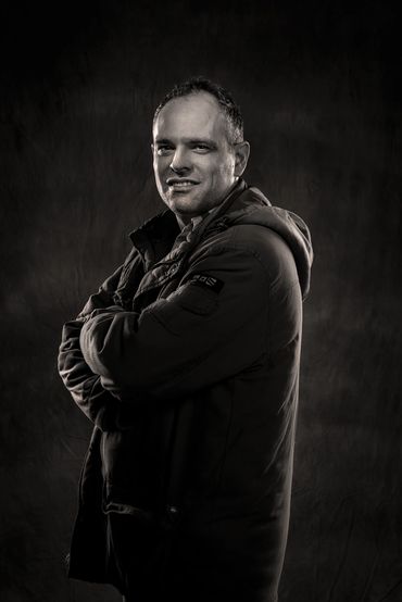 actor headshot of a man in a heavy coat, in black and white