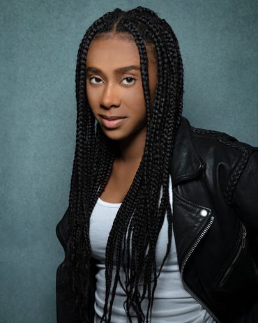 headshot of a young black woman with braids and a leather jacket in studio