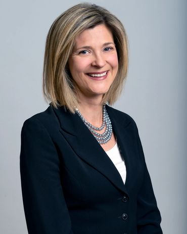 corporate headshot of a smiling woman with a grey background