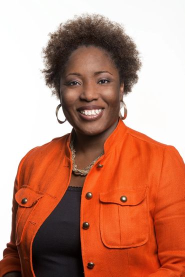 business headshot of a woman in an orange jacket on a white background