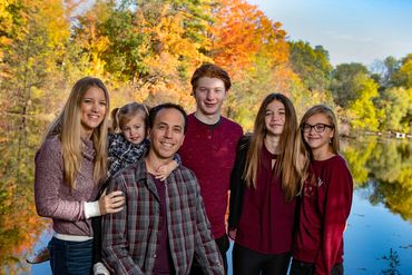 portrait of a family of six in front of a pond during the fall season 