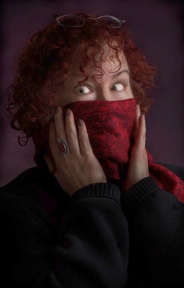 headshot of a woman with red hair covering her nose and mouth with a scarf