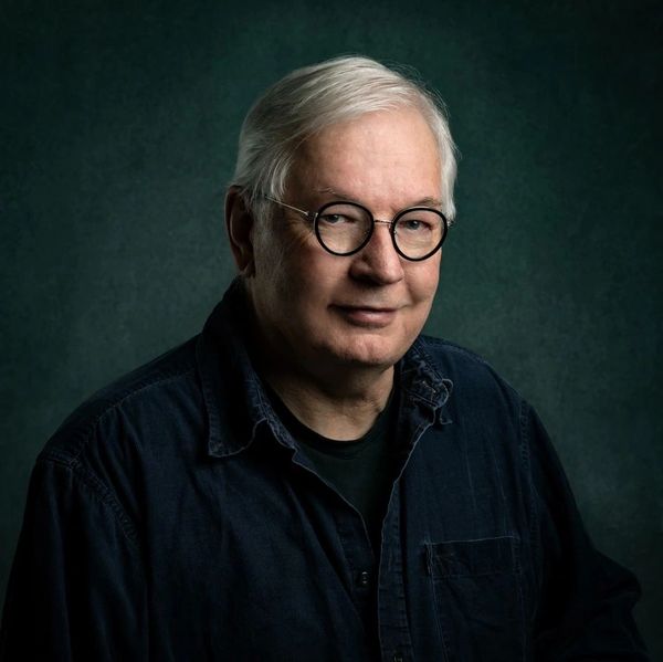 portrait of the artist in Mississauga, with grey hair and glasses in a studio 