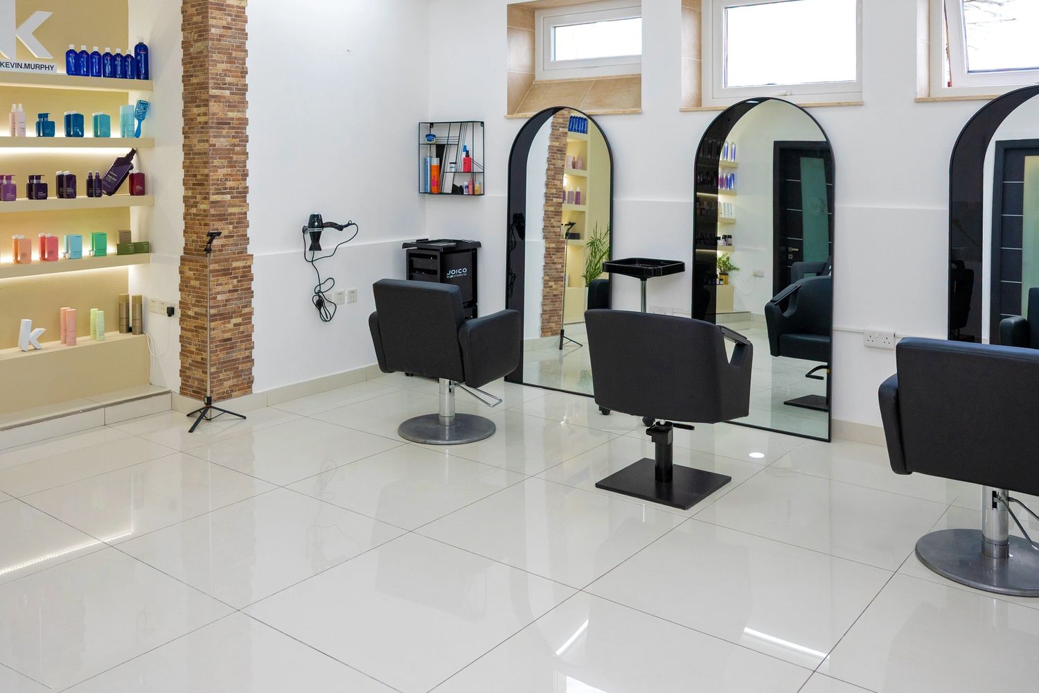 Modern hair salon interior with stylish chairs and product shelves.