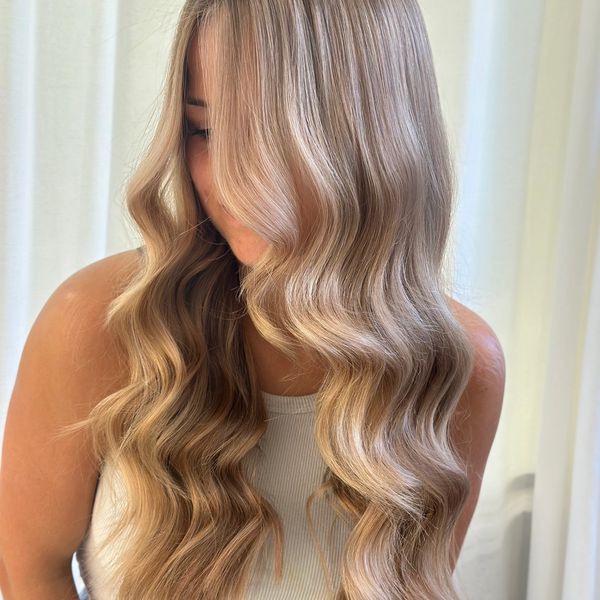 Woman with long, wavy blonde hair covering part of her face.