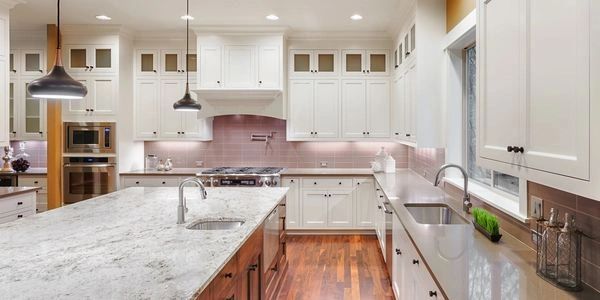 A well-lit, modern kitchen with white cabinets, a large island, and stainless steel appliances.