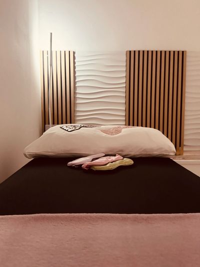 Minimalist treatment room with textured and wooden wall panels, soft lighting and soft furnishing.