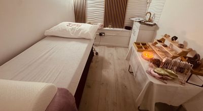 A calm therapy room with soft lighting, a treatment bed and a table with crystals and candles.
