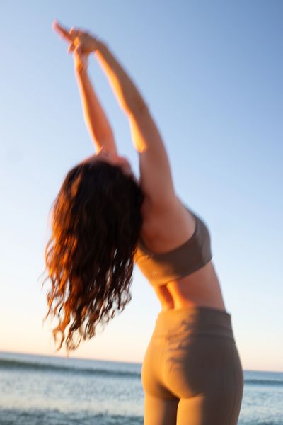 Woman stretching by the seaside at sunset.