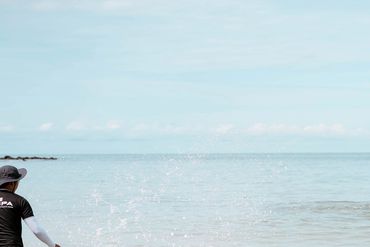 Person in hat playing at the beach with ocean waves.