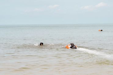 Two people swimming in the sea with one using a floatation device.