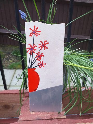 Long piece of broken bathroom tile with orange vase filled with orange flowers on a silver table
