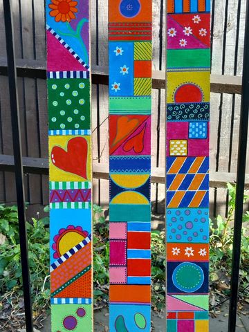 3 long wooden batons filled with colourful patterns