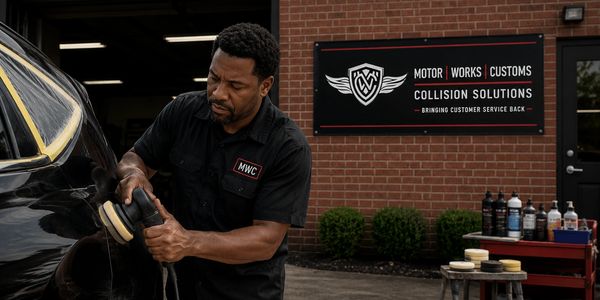 Man polishing a black car at a collision repair shop.