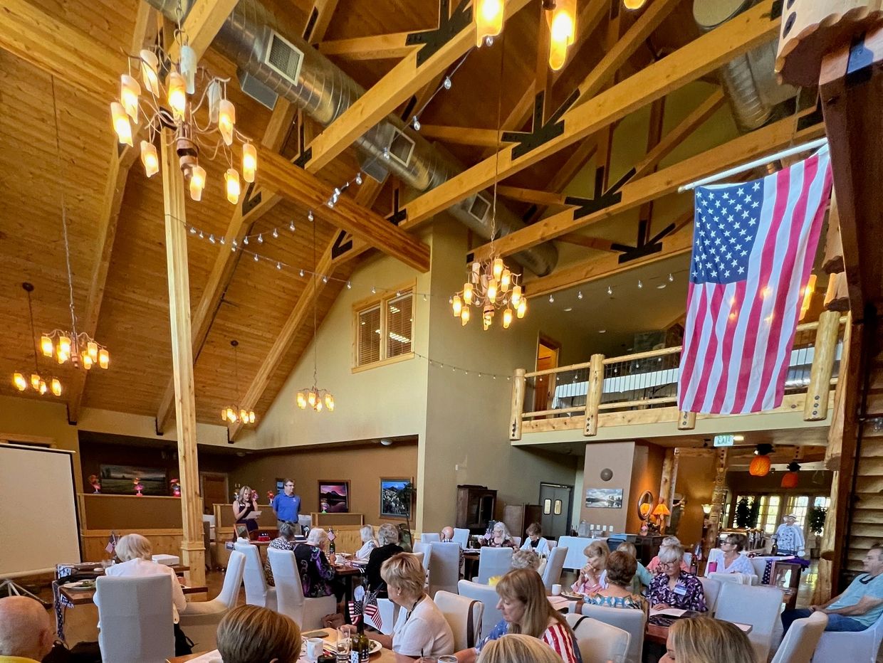 Group of people dining and listening to speakers in a cozy lodge setting.