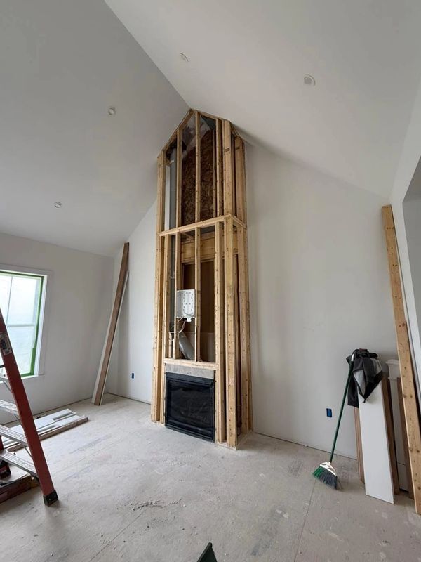 Interior room under construction with exposed wooden framing and fireplace.
