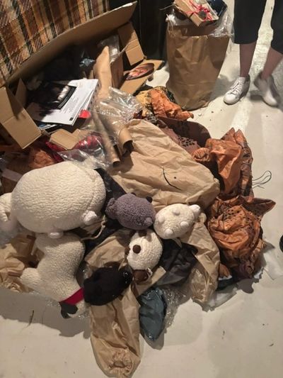 Pile of stuffed animals and clothes on the floor.
