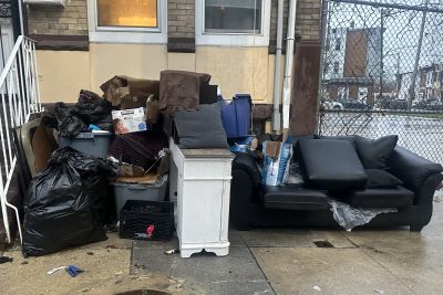 Discarded furniture and trash on a city sidewalk.