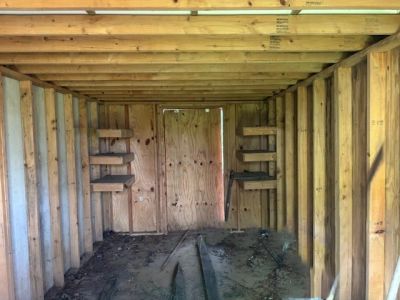 Inside view of an unfinished wooden shed or small structure.