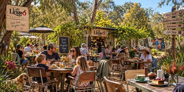 Outdoor café with people dining and relaxing in a sunny garden setting.