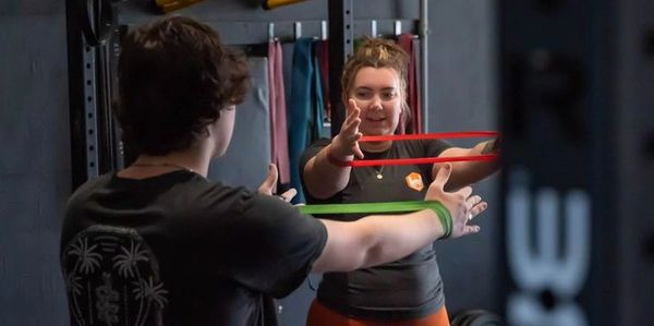 Two people using resistance bands for exercise in a gym.
