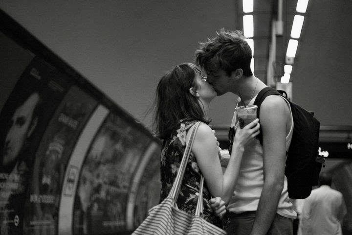 A couple kissing in a subway station.
