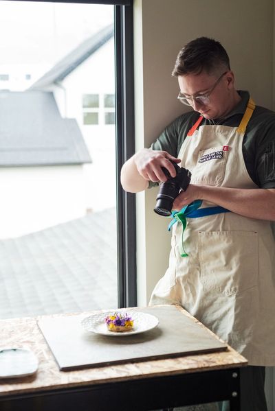 Person photographing a plated dish by the window.