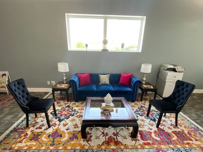 Elegant living room with blue velvet furniture and vibrant patterned rug.