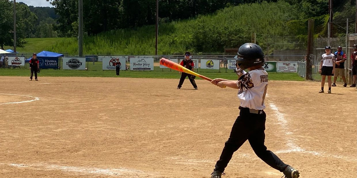 Young kids playing baseball on a sunny day at a local field.