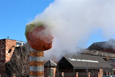 Orange-faced person statue with smoke covering the face