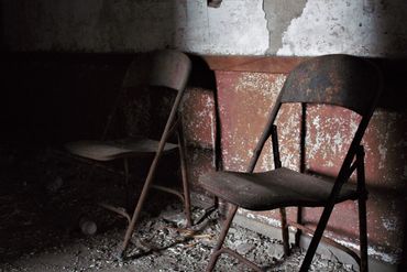 Two rusted chairs in a deserted building