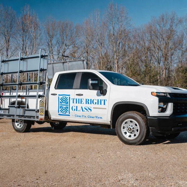 White Chevrolet truck with glass rack and company branding.