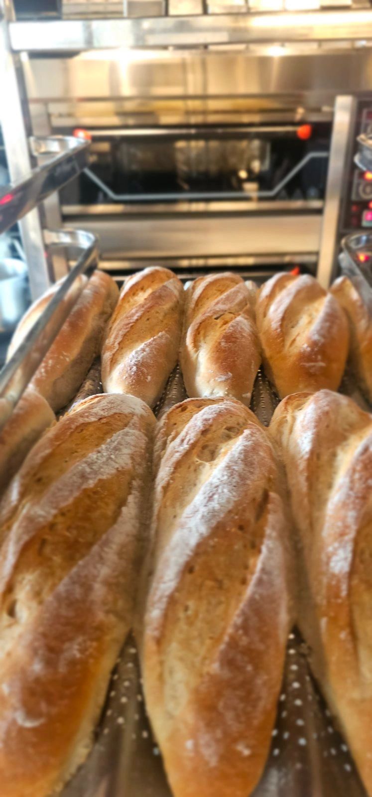 Freshly baked baguettes cooling on a rack in a bakery.